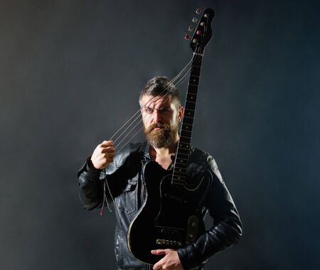 Music party. Sexy guitarist with musical instrument. Handsome rock star in leather jacket. Music concept. Bearded man with electric guitar. Guitarist with bass guitar. Musician holds electric guitarの写真素材