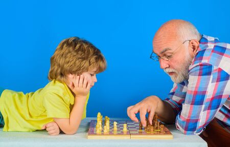 Family relationship with grandfather and grandson. Child playing chess with grandpa. Senior man thinking about his next move in game of chess. Game of chess. Grandfather teaching grandson play chessの写真素材