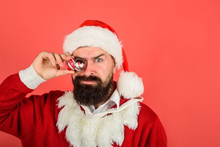 Decoration element. Santa Claus holds crystal ball. Santa with small Christmas snow globe. Christmas snowglobe in hand. Christmas decoration in hand. Bearded Santa man holds snow ball. Copy spaceの写真素材