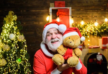 Christmas holidays. Santa claus holds plush toy. Christmas decoration. Merry christmas. Happy new year. Santa man with toy teddy. Happy Santa Claus with teddy bear. Bearded man in Santa Claus costumeの写真素材
