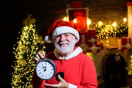 Santa man hold New year clock. Christmas clock. Winter holidays. Time to celebrate. New year party. Merry Christmas. Happy new year. Christmas time. Santa celebrate Christmas. Santa Claus holds clockの写真素材