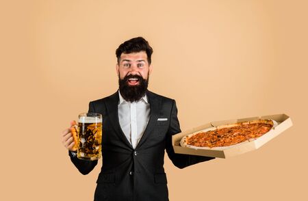 Restaurant or pizzeria. Bearded man with tasty pizza and beer in hands. Smiling man with beard holds...