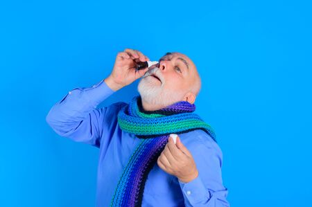 Treatment for allergies or common cold. Senior man using nasal spray. Bearded man uses spray drops of medicine in his nose. Man spraying drops in his nose. Man with nasal drops. Rhinitis, allergyの写真素材