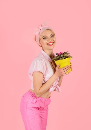 Smiling pinup girl holding flowers in pot. Girl cultivating flowers. Woman take care of flowers. Pin-up girl holding flower pot. Flowers. Violetsの写真素材