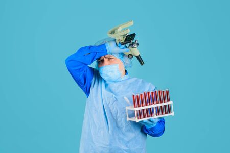Tired doktor working with blood sample in laboratory. Scientist with test tubes and microscope in clinical laboratory. Medical equipment. Blood test. Scientist working with blood sample in laboratoryの写真素材
