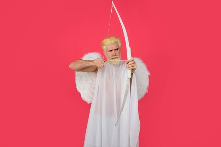 God of love. Cupid. Amour. Cupid with bow. February 14. Cupid angel with bow and arrows. Symbol of love. Happy Valentines Day. Serious man in angel costume. Valentines day angel. Cupid shoot with bowの写真素材