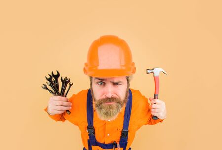 Builder in construction helmet. Repairment tools. Industrial worker. Repair. Smiling worker holds repair tools. Building. Industry. Technology. Spanner. Bearded builder. Hard hat. Hammer. Screwdriverの写真素材