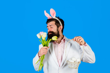 Easter celebration. Religion symbol. Preparing for Easter. Easter eggs. Surprised bearded man in suit hold egg and flowers. Happy Easter. Bearded man. Eggs hunt. Rabbit costume. Holidaysの写真素材