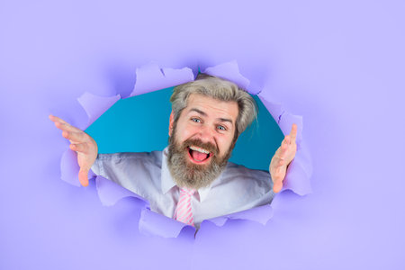 Business growth. Through paper. Bearded man looking through paper. Advertising. Copy space for advertising, to insert text or slogan. Discount, sale, season sales.の写真素材