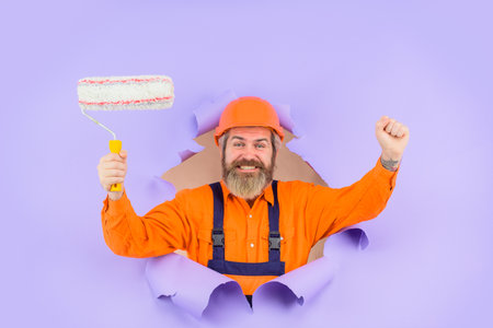 Through paper. Bearded builder look through paper. Painter. Bearded painter with paint roller....