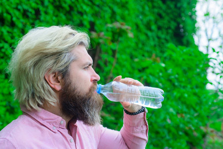Bearded man drinking water. Hydration concept. Aqua. Dehydration. Man drink water outdoor. Man with water bottle. Healthy lifestyle. Health care concept. Drinking water. Drinkの写真素材