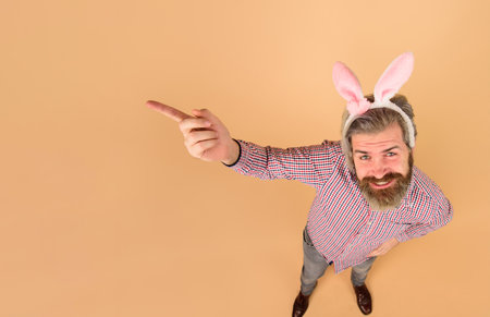 Easter man points finger on copy space. Sale. Discount. Season sales. Happy Easter. Man in bunny...