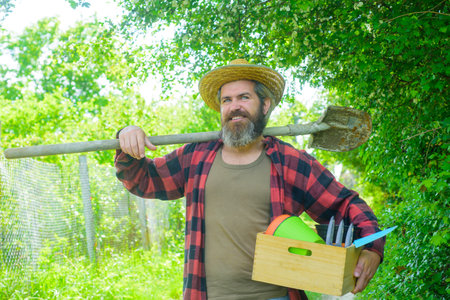 Gardener work. Farm. Happy bearded man in garden. Plants. Garden tools. Gardening. Eco-farm. Work in garden. Bearded man with gardening tools. Work in gardenの写真素材
