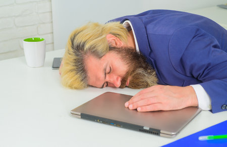 Office worker. Tired businessman sleep in office. Sleepy bearded manat table. Leadership. CEO. Business expert. Businessman. Emotional. Office work. Businessman in suit.の写真素材