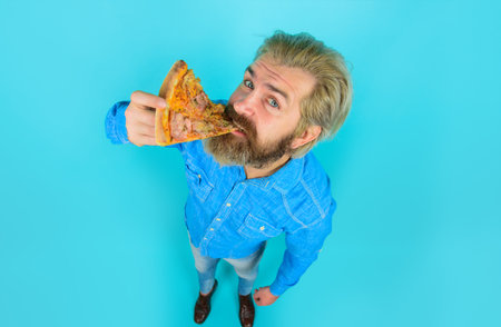 Man eating pizza. Fast food. Pizzeria. Bearded man eats slice of pizza. Italian cuisine concept. Tasty pizza. Lunch or dinnerの写真素材