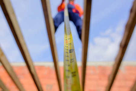 Builder equipment. Measuring device. Selective focus. Builder with tape measure. Construction worker on construction site with roulette. Roofer carpenter in helmet with meter. Worker use tape measureの写真素材