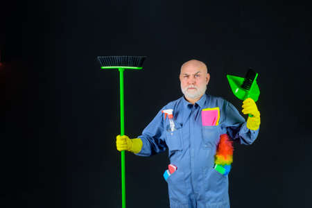 Cleaning. Man with cleaning tools. Bearded man in uniform with broom and scoop. Household. Housekeeping. Besom. Broom. Disinfection. Professional cleaning. Cleaning service. Clean upの写真素材
