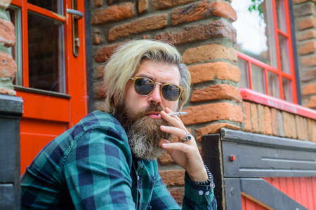 Stylish bearded man with cigarette. Smoking hipster. Sensual bearded man with cigarette. Cigarette smoke. Bearded man smoke cigarette. Handsome man smoking outsideの写真素材