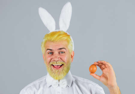 Happy man with rabbit ears with Easter egg. Male in bunny ears. Eggs hunt. Spring holidays.