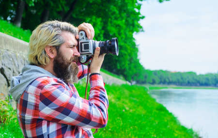Man traveler making photos near river. Travel and tourism. Male photographer with digital camera.の写真素材