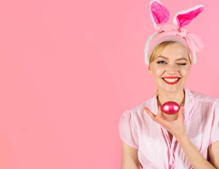 Happy Easter. Winking girl hunts for Easter eggs. Smiling woman in rabbit bunny ears with colored...