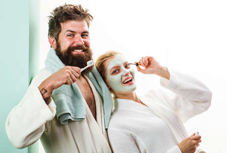 Morning treatments. Couple In bathroom. Husband and wife. Husband with tooth brush, Wife with...