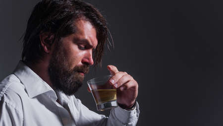 Bearded man drinks whiskey, Brandy or cognac. Degustation and tasting. Strong alcohol. Sommelier tastes drink.の写真素材