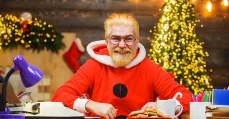 Smiling Santa Claus sitting at table. Christmas decorations. Merry Christmas and Happy New Year.の写真素材
