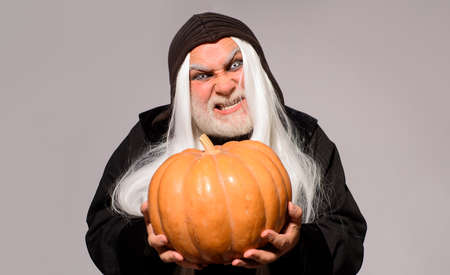 Evil wizard with orange pumpkin. Fantasy horror Halloween. Wicked Devil man with Jack-o-lantern....