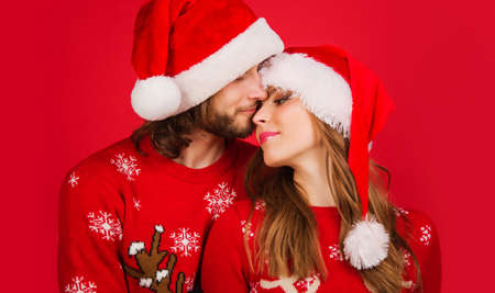 Young couple in Christmas sweaters and Santa hats. New Year advertising. Merry Christmas. Relationships concept.の写真素材