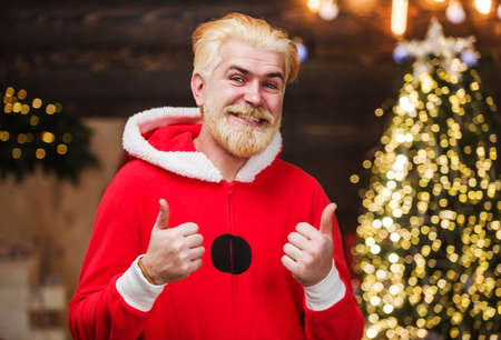 Happy Santa Claus shows thumbs up. New year advertising. Smiling Bearded man in red costume. Holidays concept.の写真素材