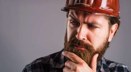 Worker in helmet. Bearded builder in hard hat. Closeup portrait of tired Engineer or architect. Copy space.の写真素材
