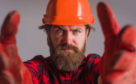 Builder in helmet. Workman in hardhat and work gloves. Building, industry, technology. Bearded Worker Closeup. Selective focus.の写真素材