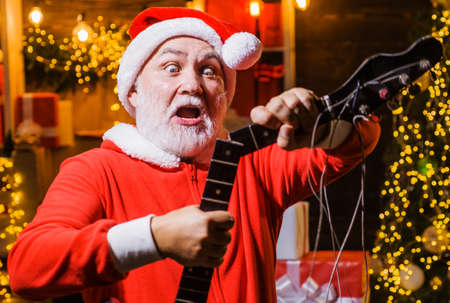 Surprised Santa Claus with broken electric guitar. Merry Christmas and happy New Year. Christmas time. Rock music.の写真素材