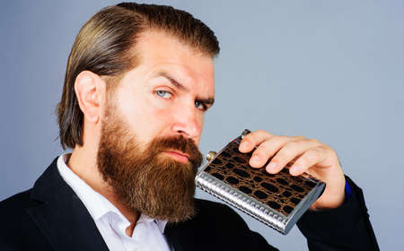Bearded man in suit with booze flask for alcohol. Businessman with metal hip flask. Alcohol drink.