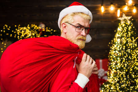 Santa Claus carrying red bag with presents. Delivery christmas gifts. New year advertising.