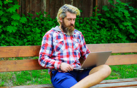 Bearded man with laptop working outdoors. Businessman with notebook in park. Study and work online.の写真素材