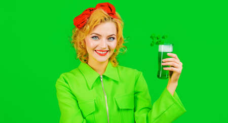 Happy girl with green beer. Patricks Day. Smiling woman drinking Green beverage with clover.の写真素材