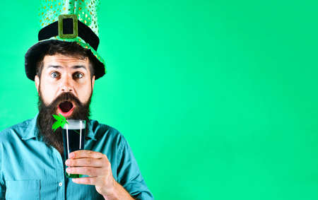 Man with glass of beer with shamrock. Saint Patricks Day. Surprised bearded male in leprechaun hatの写真素材