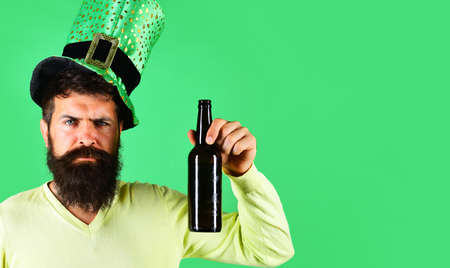 Serious man with glass of beer. Patricks Day. Irish tradition. Bearded leprechaun in green hat.の写真素材