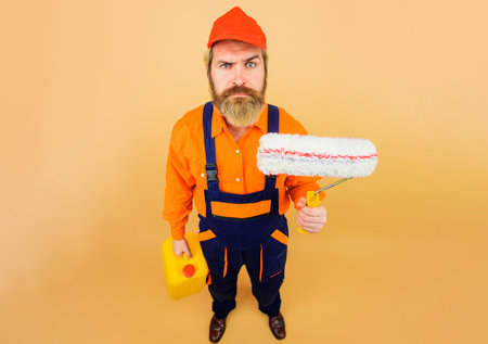 Painter with paint roller and canister. Painting concept. Professional builder in hard hat and uniform.の写真素材