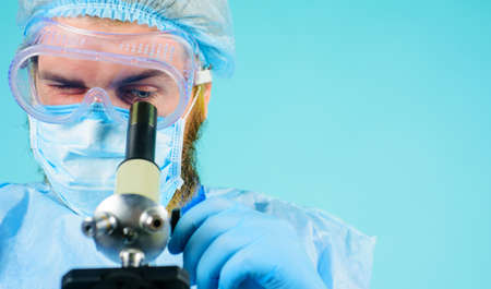 Doctor in medical mask with microscope. Microbiologist working in laboratory. Medical equipment.