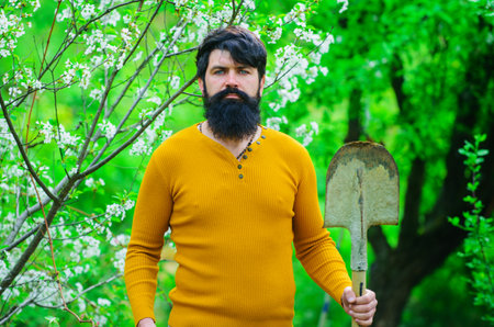 Spring. Bearded man with gardening spade preparing to planting. Farmer working in garden.の写真素材