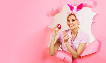 Happy woman painting easter egg. Smiling girl in bunny ears look Through paper hole. Sale. Discount.