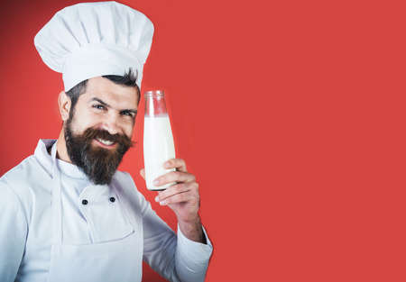 Dairy products. Smiling chef in white uniform with bottle of milk. Bearded cook with milkshake.の写真素材