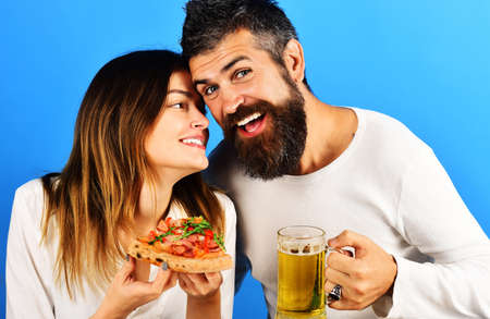 Smiling couple eating pizza and drinking beer. Happy Family enjoying fast food together.の写真素材