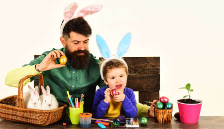 Rabbits family preparing for Easter. Father and son in bunny ears with painted eggs. Spring holiday.