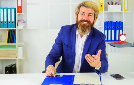 Stylish smiling businessman in suit sits at desk in modern office. business growth. leadership. CEOの写真素材