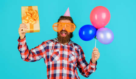 Celebrating concept. happy birthday. Happy man in funny party glasses with present box and balloonsの写真素材
