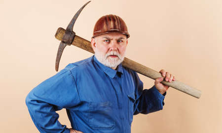 Construction worker in hard hat and uniform with pickaxe. Male laborer with building toolsの写真素材